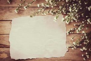 vit blomma på grunge trä styrelse och papper bakgrund med Plats. foto
