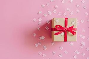brun gåva låda på de rosa bakgrund med jul dekoration. minimal styled Semester kort med kopia Plats. foto