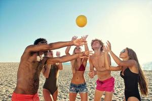 grupp av vänner spelar på strand volley på de strand foto