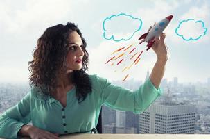 affärskvinna lanserar sitt företag med en raket. begreppet start och innovation. foto