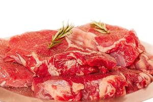 nötkött biffar på en metall tallrik. kött för matlagning med rosmarin isolerat på vit. foto