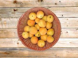 aprikoser i en flätad korg på träbordbakgrund foto