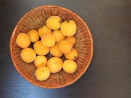 aprikoser i en flätad korg på mörk bordsbakgrund