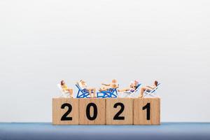 miniatyrfolk som bär baddräkter som sitter på träklossar med siffror 2021 foto