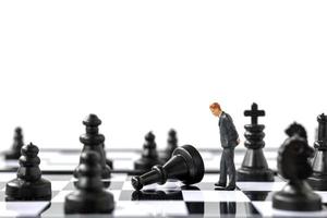 miniatyraffärsman som står på ett schackbräde, affärs- och konkurrensbegrepp foto