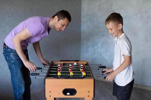 söt pojke spelar tabell fotboll med hans emotionell pappa i de rum foto