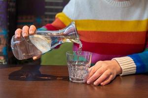 Häll i vatten med citron- från en kanna in i en glas. färgrik kläder foto