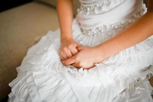 de brudens händer på de bakgrund av en vit bröllop klänning foto