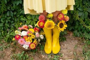 fötter i gul sudd stövlar med höst blommor nära de vingård foto