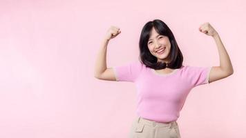 porträtt ung asiatisk kvinna stolt och självsäker som visar stark muskel styrka vapen böjd poserar, känner handla om henne Framgång prestation. kvinnor bemyndigande, jämlikhet, friska styrka och mod begrepp foto