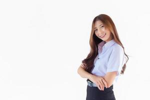 porträtt av ett vuxen thai studerande i universitet studerande enhetlig. asiatisk söt flicka stående med henne vapen korsade självsäkert isolerat på vit bakgrund. foto