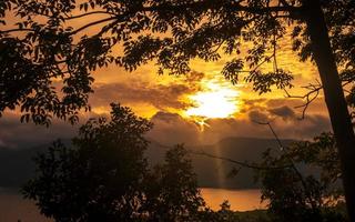 gyllene timme solnedgång panorama med sjö Översikt och silhuett av träd foto