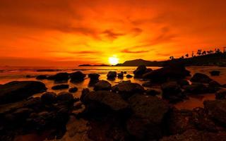 gyllene timme solnedgång. orange solnedgång på havet med stenar foto