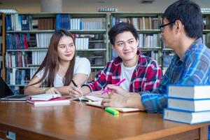 en grupp av asiatisk studenter Sammanträde och diskuterar läsa böcker tillsammans inuti de bibliotek. foto