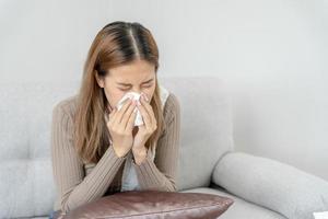 sjuk kvinna med en huvudvärk och känsla kall på soffa, kvinna nysning och rinnande näsa med säsong- influensa, allergisk, hög feber och influensa, vilar, virus, coronavirus, känna sjukdom, respiratorisk foto