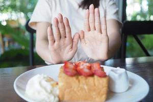 kvinnor vem kontrollera vikt tryckte de efterrätt tallrik bort. diet begrepp foto