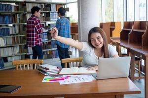 kvinna studenter är betonade med läsning en massa av böcker placerad på de tabeller i de bibliotek. till förbereda för de examen foto