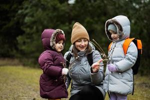 mor med döttrar innehav vide kvistar i skog. foto