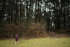 bebis flicka gående längs de skog efter regn. foto