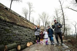 familj turist med tre barn stå på våt väg till ett gammal medeltida slott fästning i regn. foto