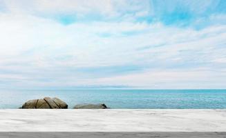 marmor textur tabell topp över hav strand hav med moln och blå himmel, display glansig marmor golv på tropisk hav strand, klippa sten, bakgrund bakgrund med kopia Plats för sommar produkt presentation foto