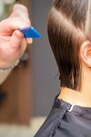 frisör håller på med frisyr av ung kvinna foto