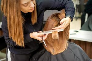 frisör nedskärningar hår till ung kvinna foto