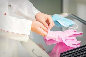 sjuksköterska händer sätta på rosa handskar foto
