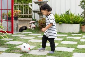 söt liten pojke spelar fotboll med boll utomhus på fotboll fält foto