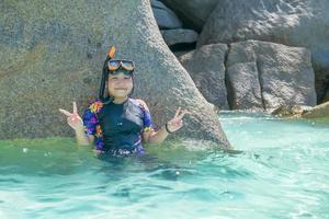 Lycklig söt flicka med ansikte masker och snorklar, hav i bakgrund. foto