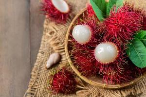 topp se av färsk rambutan frukt med löv på bambu korg foto