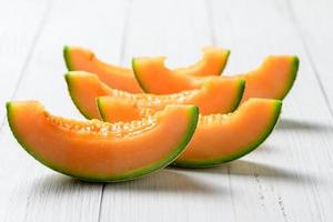 skivad av japansk meloner, honung melon eller cantaloupmelon på vit trä- tabell foto