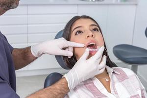 beskära manlig stomatolog passande dental inriktare på kvinna patient tänder foto