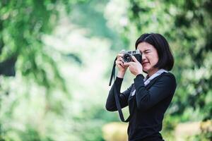 ung Söt kvinna använda sig av kamera tar Foto i natur parkera