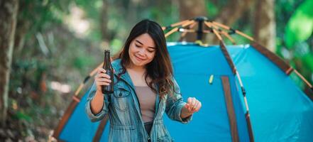 ung kvinna heja på och dryck dryck främre av camping tält foto