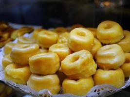stänga upp selektiv fokus typisk efterrätt deg i alcala stil, rosquillas de alcala, puff bakverk med gul ägg äggula beläggning med sirap, ringa formad, munkar, i bakverk affär foto