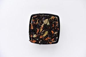 svart te med kryddor i en glas kopp på en vit bakgrund. utsökt te. torr te. foto