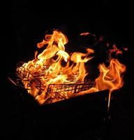 metall netto över brand brinnande kol glödande kol trä i utegrill grill på natt foto