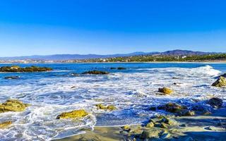 skön stenar klippor surfare vågor på strand puerto escondido Mexiko. foto