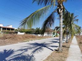 färgrik gata med hus palmer bilar restauranger puerto escondido Mexiko. foto