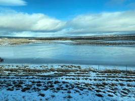 isländsk vinter- landskap med snö täckt kullar och blå molnig himmel foto