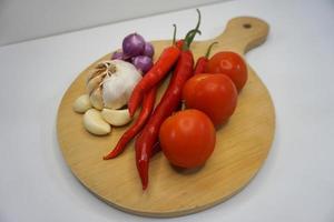 vitlök, chili, röd lök och tomater på en trä- underlägg, hög vinkel skott. foto