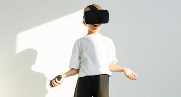 liten pojke bär virtuell verklighet glasögon i enkel isolerat vit bakgrund foto