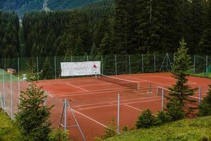 tennis domstol och omgiven förbi träd och kullar. de perfekt plats för avslappning och övning för en Bra hälsa foto