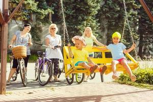 tema familj aktiva sporter utomhus- rekreation. en grupp av människor är en stor familj av 5 människor stående Framställ Cyklar i en stad parkera på en väg på en solig dag foto