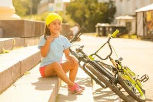 liten flicka ridning en cykel i en stad foto