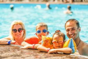 Lycklig familj i simning slå samman på vatten parkera foto