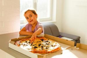 liten barn flicka njut av äter pizza foto