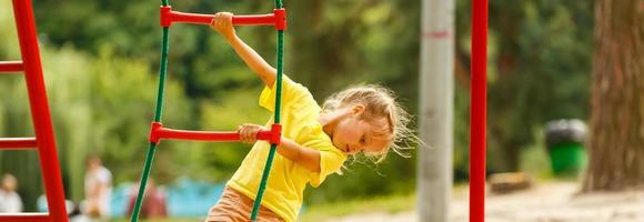 söt liten flicka har roligt på en lekplats utomhus i sommar foto