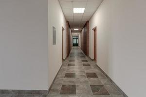 vit tömma lång korridor med röd tegel väggar för rum kontor i interiör av modern lägenheter, kontor eller klinik foto